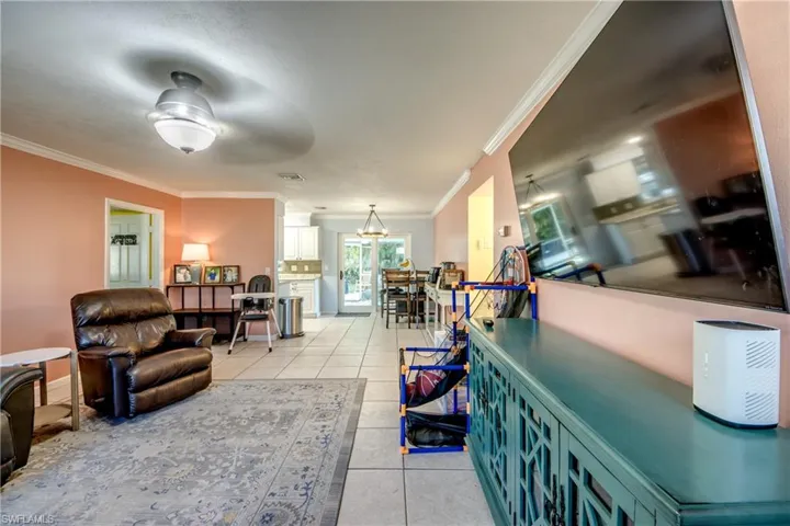 Living area with ornamental molding, light tile patterned flooring, and ceiling fan