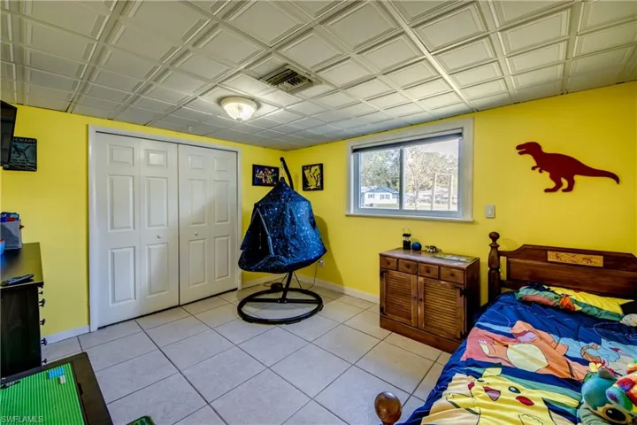 Bedroom with a closet, light tile patterned floors, and an ornate ceiling