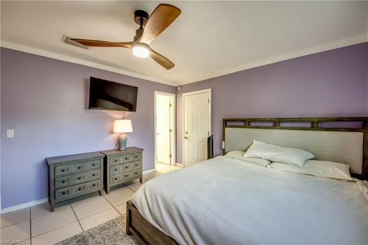 Bedroom featuring a ceiling fan, light tile patterned floors, and ornamental molding