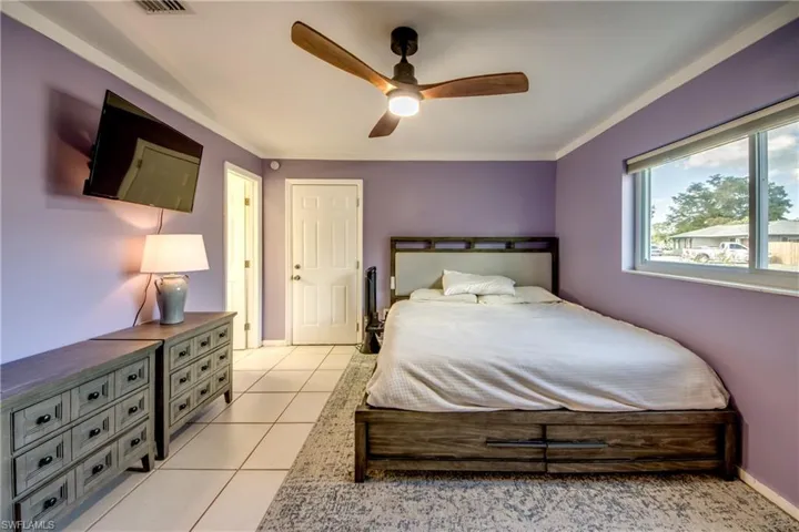Bedroom featuring ceiling fan, ornamental molding, and light tile patterned floors