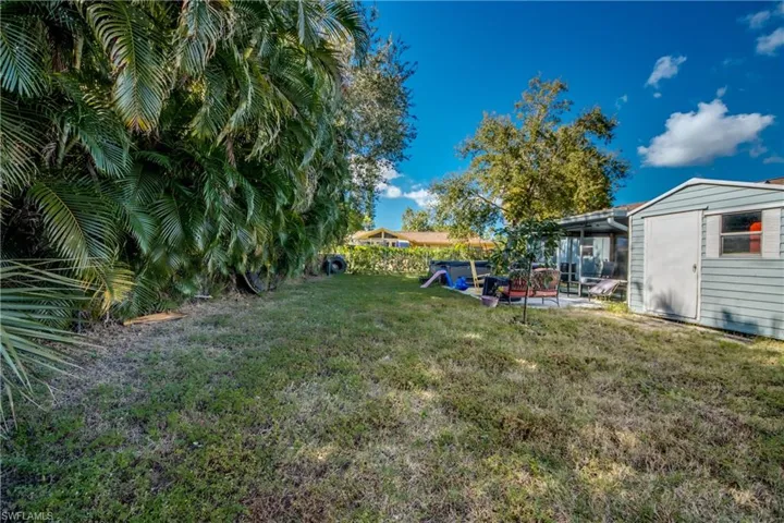 View of yard featuring a sunroom, an outdoor structure, and a patio
