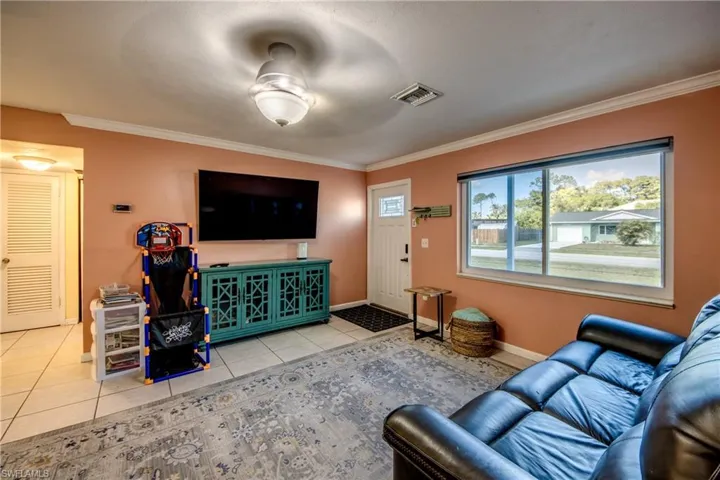 Living room with tile patterned floors and ornamental molding