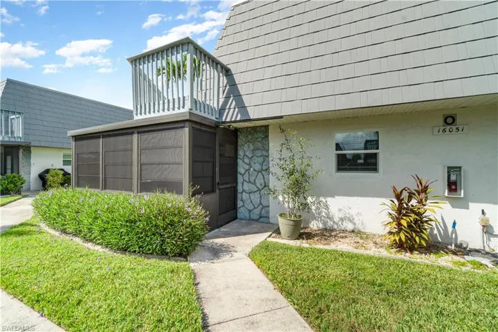 View of exterior entry with a yard and stucco siding