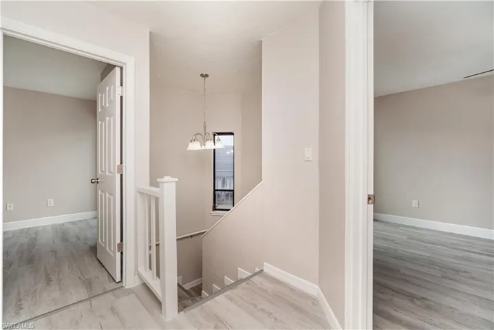 Stairs with wood finished floors and hanging lights
