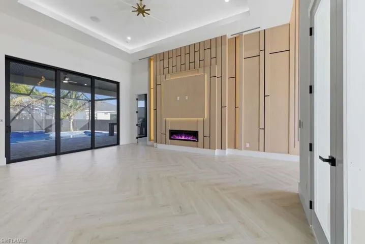 Unfurnished living room featuring a warm lit fireplace, parquet flooring, and a raised ceiling