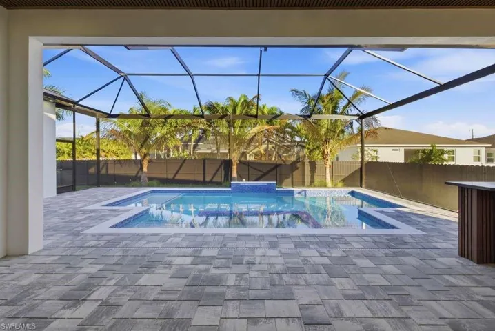 View of pool featuring a sunroom, patio surround, a lanai, a fenced backyard, and a jacuzzi