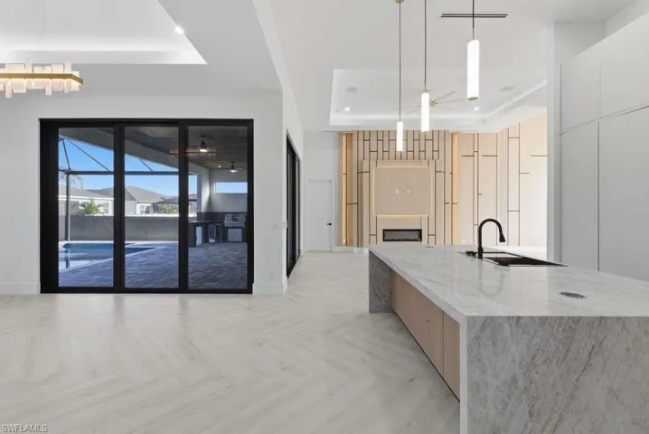 Kitchen with a raised ceiling, parquet floors, decorative light fixtures, light stone counters, and modern cabinets