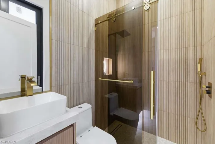 Bathroom with walk in shower, vanity, and tile walls