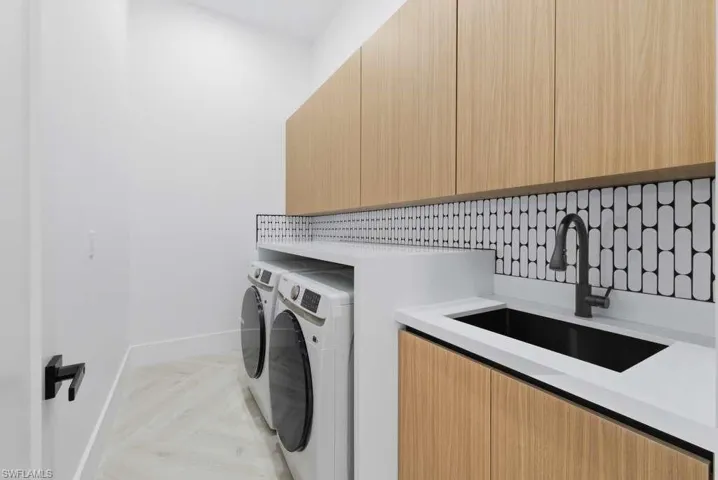 Laundry room featuring washer and clothes dryer, parquet floors, and cabinet space