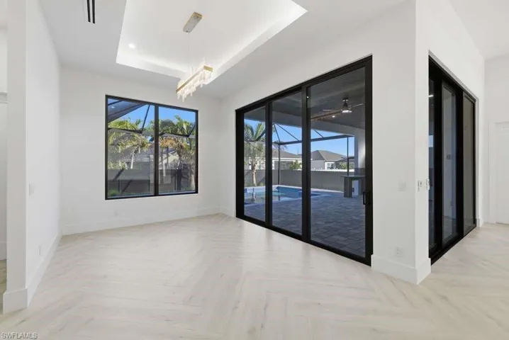 Spare room featuring a raised ceiling, parquet floors, a ceiling fan, and a chandelier