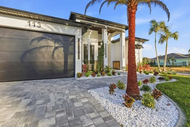 Entrance to property with driveway, stucco siding, and a garage