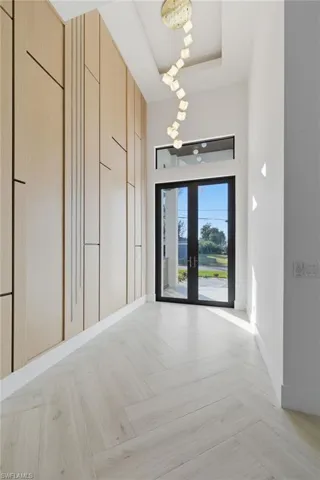 Hallway with a tray ceiling, parquet flooring, and french doors