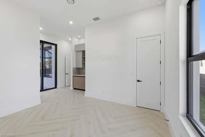 Empty room with parquet flooring and recessed lighting