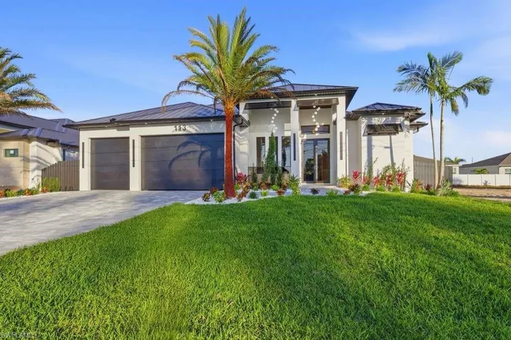 View of front of house featuring stucco siding, decorative driveway, an attached garage, and french doors