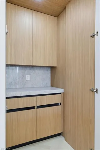 Kitchen view of modern cabinets, backsplash, light wood finish cabinetry, and light stone counters