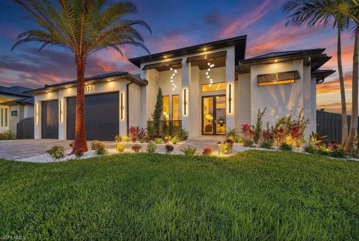 View of front facade with stucco siding, a garage, french doors, and driveway