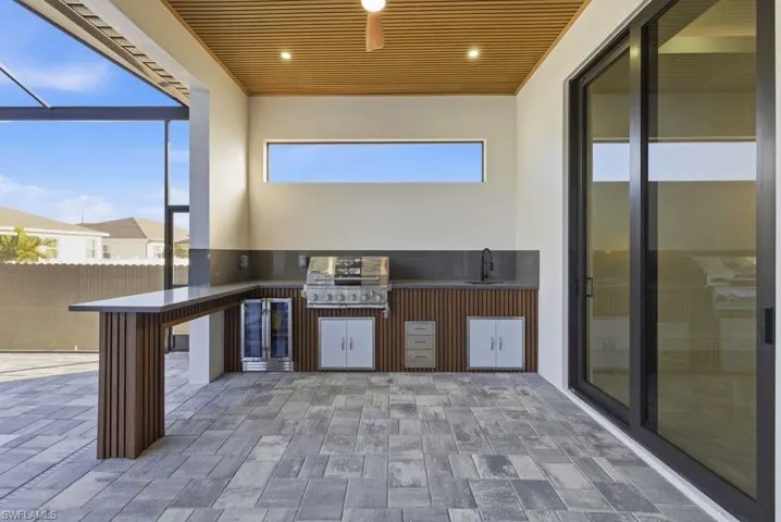 View of patio with area for grilling, a sunroom, and a lanai