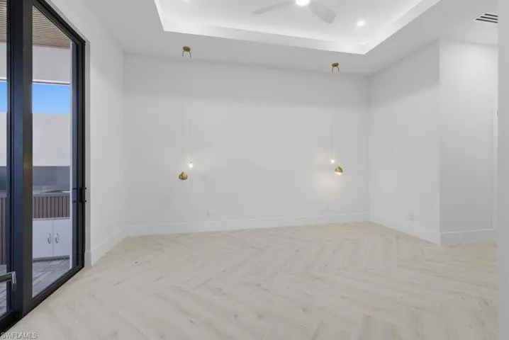 Empty room featuring parquet flooring, a raised ceiling, a ceiling fan, and recessed lighting