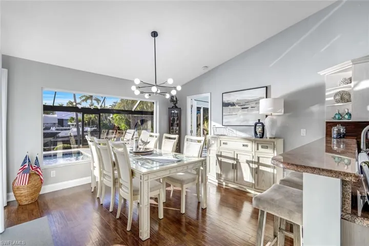 Dining room with vaulted ceiling, a chandelier, and dark wood-style flooring