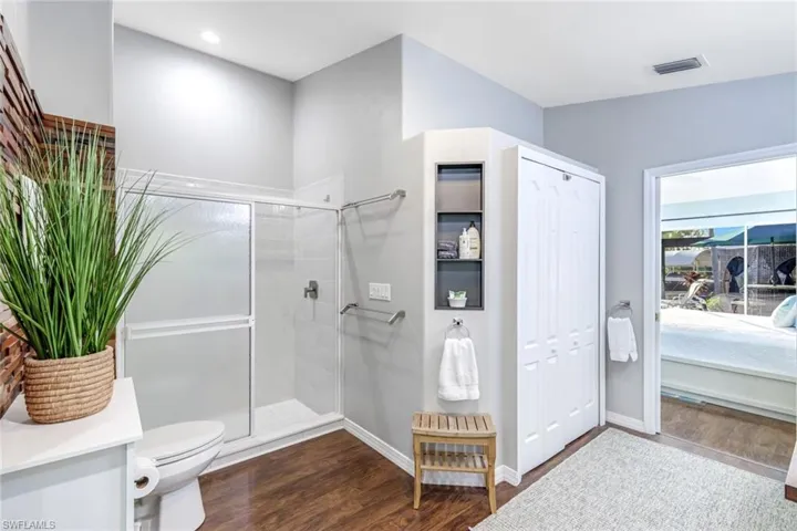 Ensuite bathroom featuring dark wood finished floors, a closet, a stall shower, and vanity