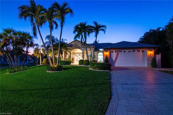 Ranch-style home with a front yard, decorative driveway, a garage, and stucco siding