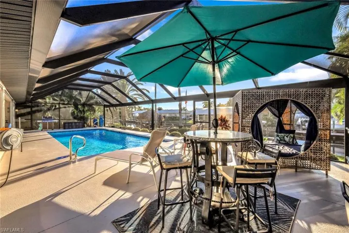 Swimming pool with a lanai, a patio, a sunroom, and outdoor dining space