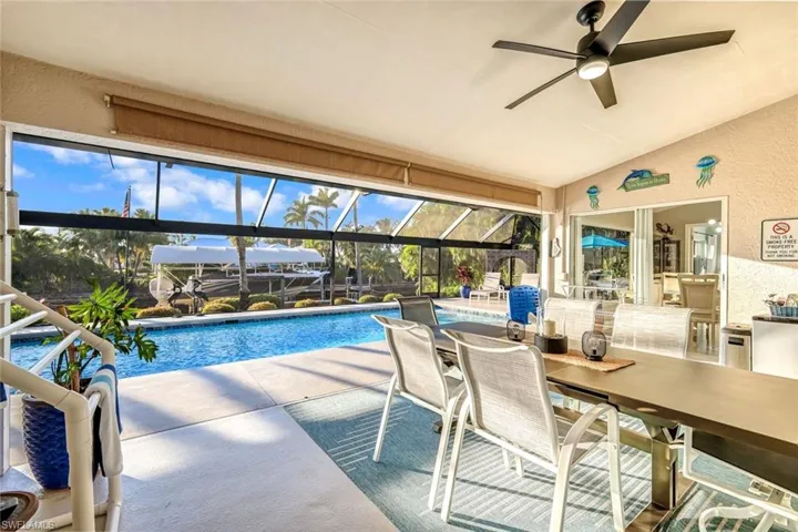 Outdoor pool featuring a sunroom, outdoor dining area, a lanai, a patio, and ceiling fan
