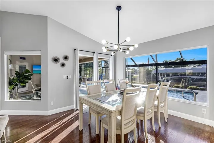 Dining space with a chandelier, dark wood-style flooring, and high vaulted ceiling