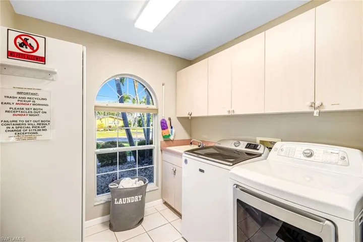Laundry area featuring cabinet space, light tile patterned flooring, and separate washer and dryer