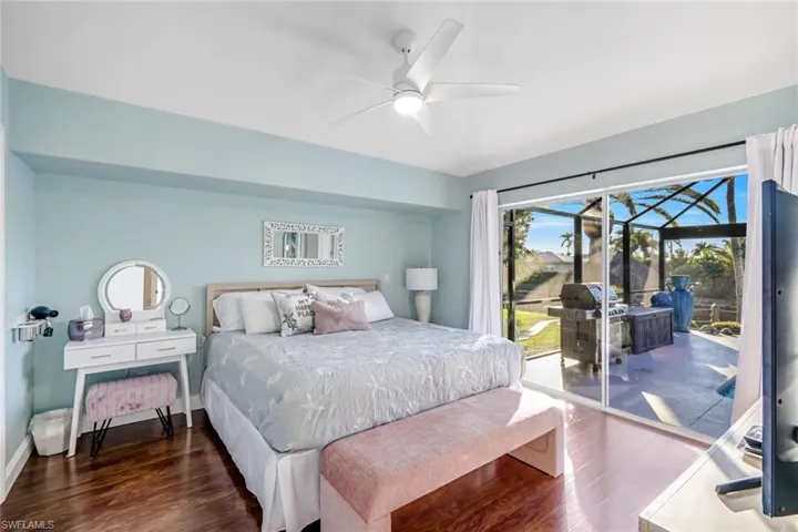 Bedroom featuring dark wood finished floors, a sunroom, access to outside, and a ceiling fan