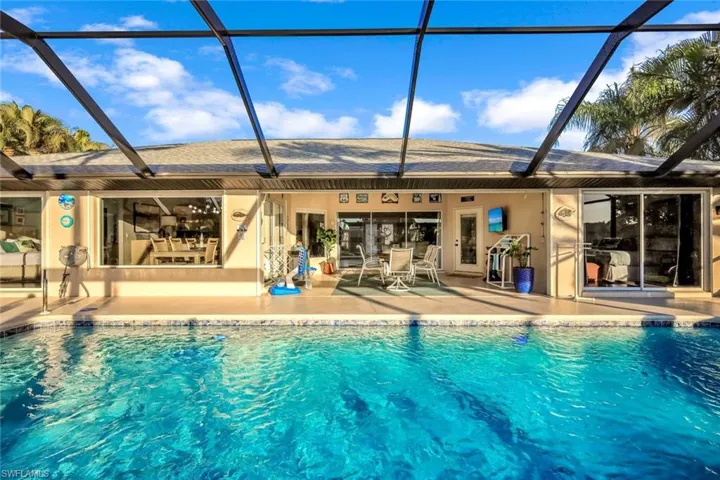 Outdoor pool with glass enclosure, a sunroom, and a patio area