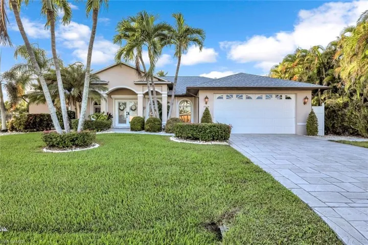 View of front of home featuring stucco siding, french doors, a front yard, and decorative driveway