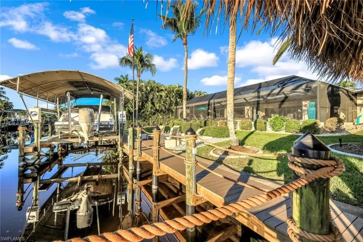 Dock featuring boat lift, a lanai, a water view, and a sunroom