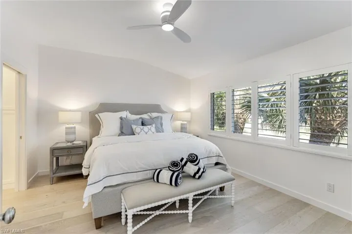 Bedroom featuring light wood-type flooring, lofted ceiling, and a ceiling fan