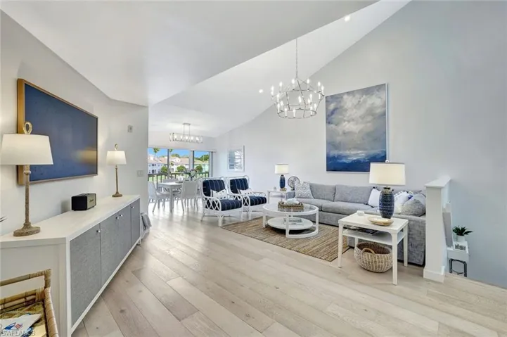 Living room with high vaulted ceiling, light wood-style floors, and a chandelier