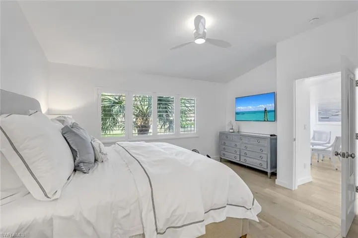 Bedroom with vaulted ceiling, light wood-style flooring, and ceiling fan