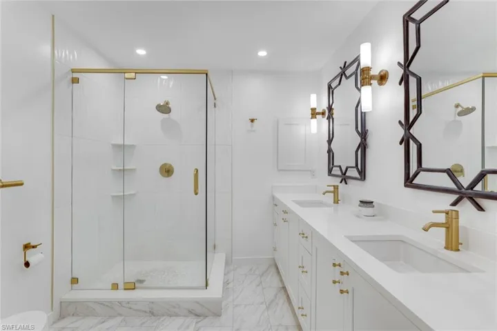 Full bathroom with a shower stall, double vanity, light marble finish floors, and recessed lighting