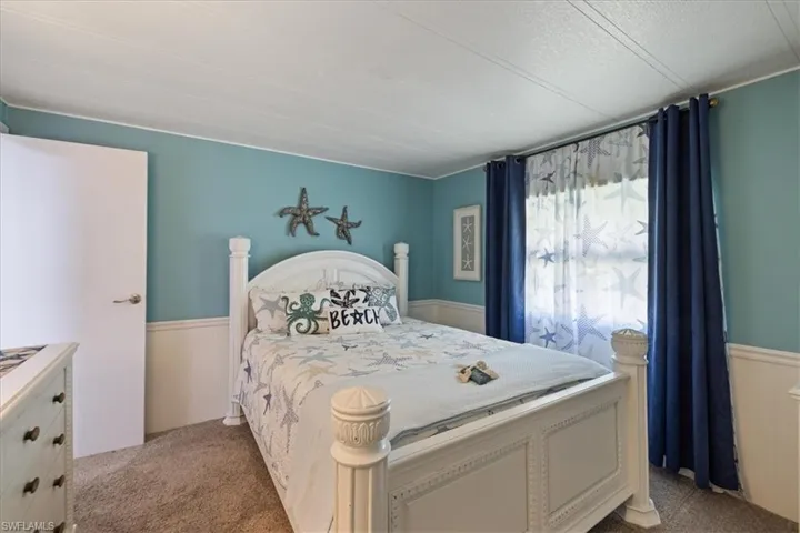 Bedroom with light colored carpet and wainscoting