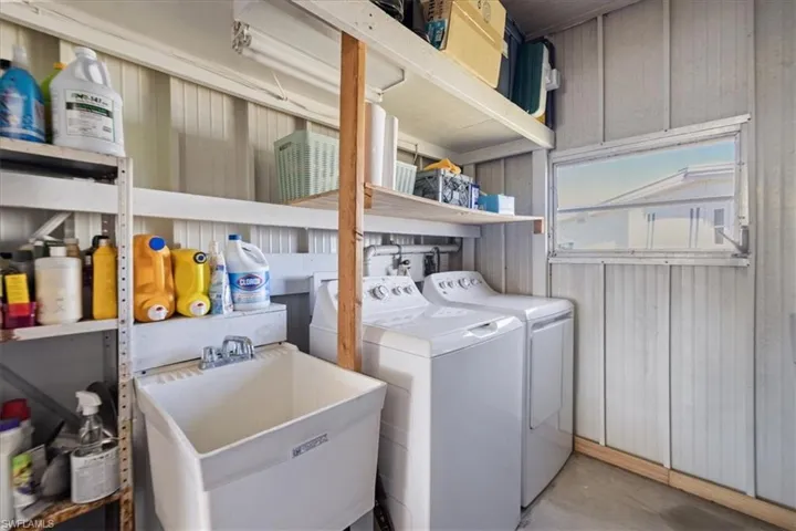 Laundry area with washing machine and clothes dryer, laundry area, wooden walls, and a sink