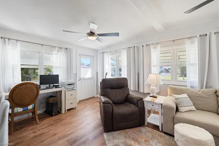 Living area with light wood finished floors, beamed ceiling, and a ceiling fan