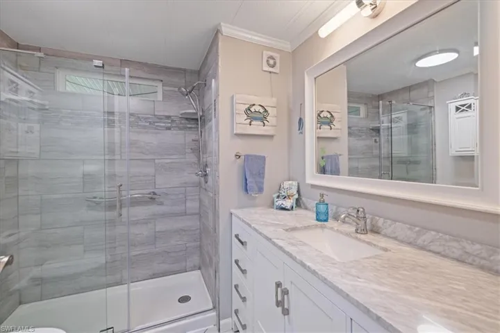 Full bath with a stall shower, vanity, and crown molding