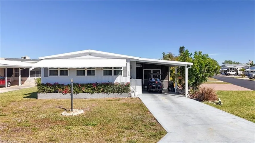 Manufactured / mobile home with an attached carport, concrete driveway, and a front lawn