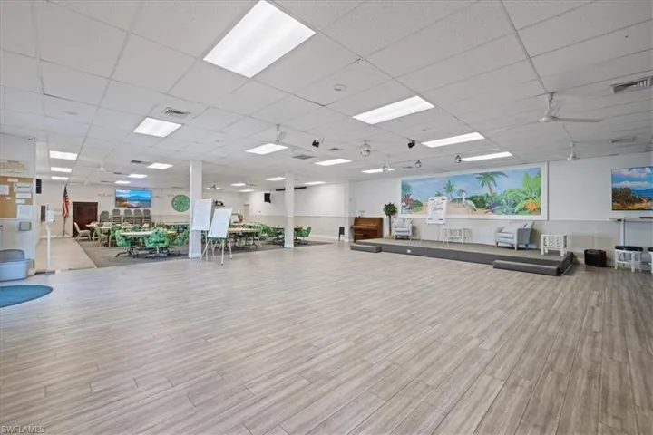 Exercise room with wood finished floors, visible vents, and a paneled ceiling