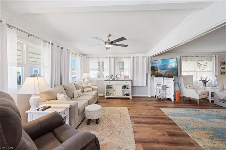 Living room featuring crown molding, wood finished floors, a ceiling fan, and vaulted ceiling
