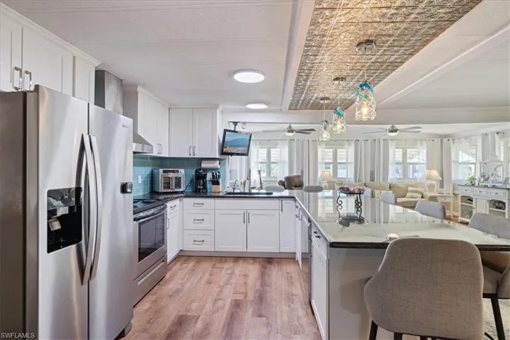 Kitchen featuring a ceiling fan, a sink, stainless steel appliances, open floor plan, and light wood-type flooring