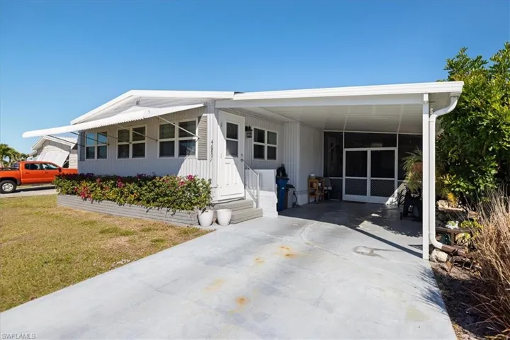Manufactured / mobile home featuring a carport, driveway, and a front yard