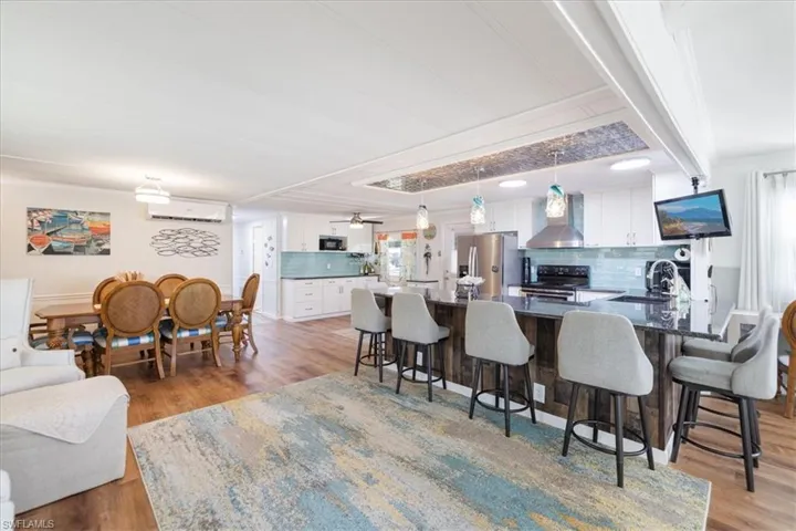 Kitchen featuring a kitchen bar, a sink, stainless steel appliances, a peninsula, and wall chimney exhaust hood