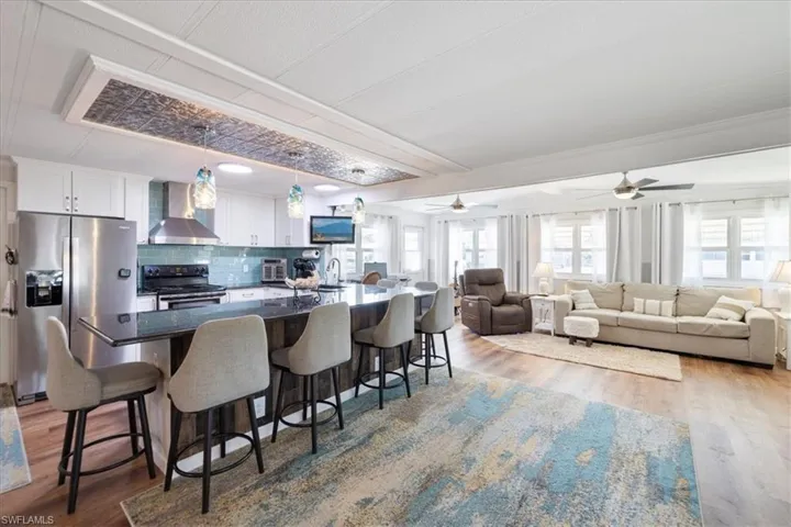 Kitchen with plenty of natural light, a kitchen breakfast bar, stainless steel appliances, and wall chimney exhaust hood