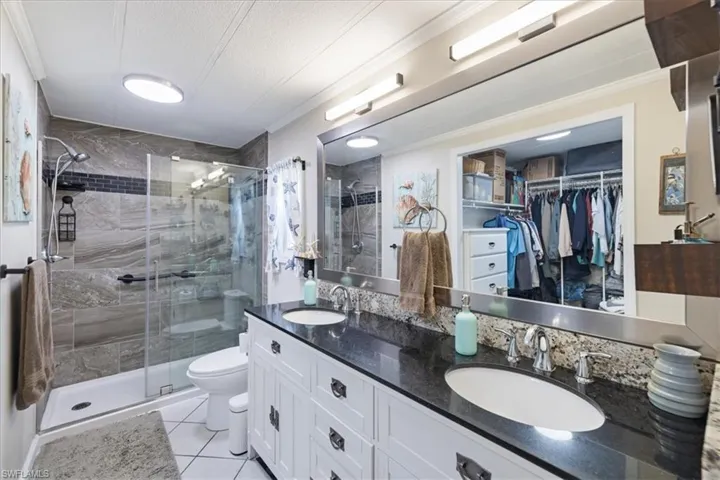 Full bathroom with ornamental molding, toilet, a stall shower, and a sink