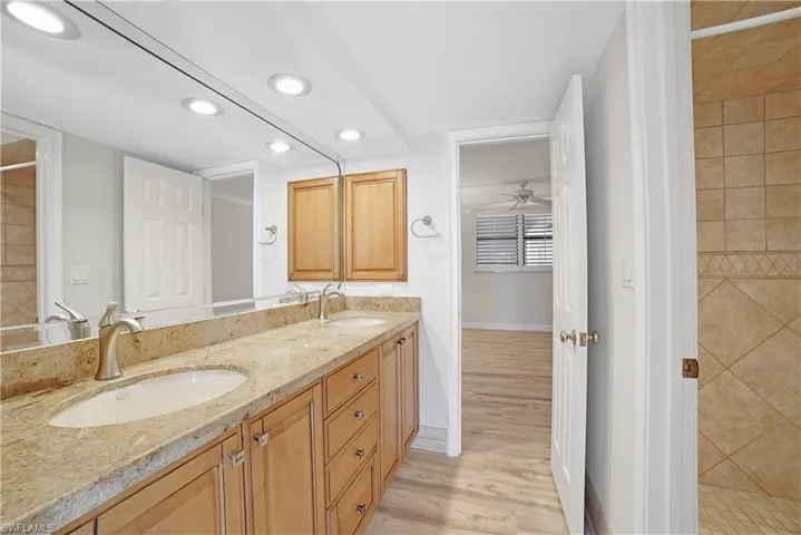Bathroom featuring hardwood / wood-style floors, ceiling fan, vanity, and a tile shower